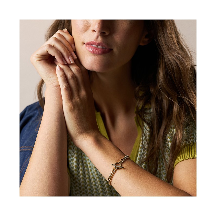 Ein zierliches goldfarbenes Fossil Armband aus Edelstahl mit Glassteinen, getragen von einem Model.
