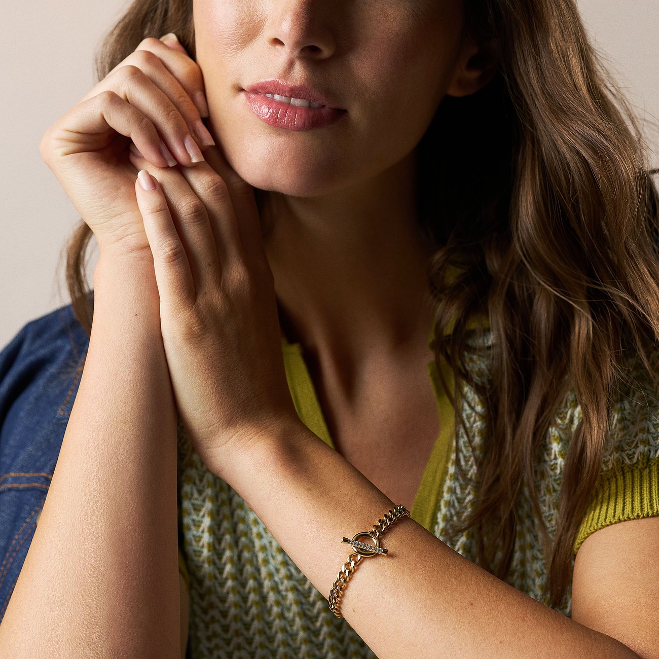 Ein zierliches goldfarbenes Fossil Armband aus Edelstahl mit Glassteinen, getragen von einem Model.