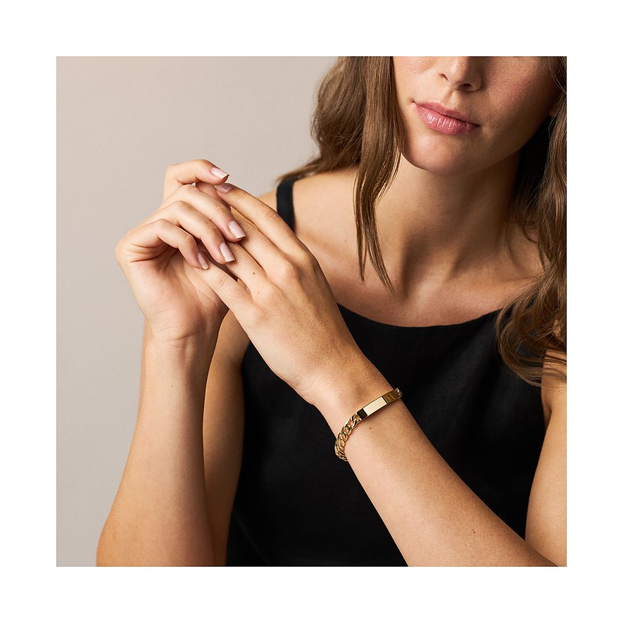 Am Handgelenk einer Frau getragenes Fossil Armband aus goldfarbenem Edelstahl mit Panzerkette und gravierbarem Plättchen