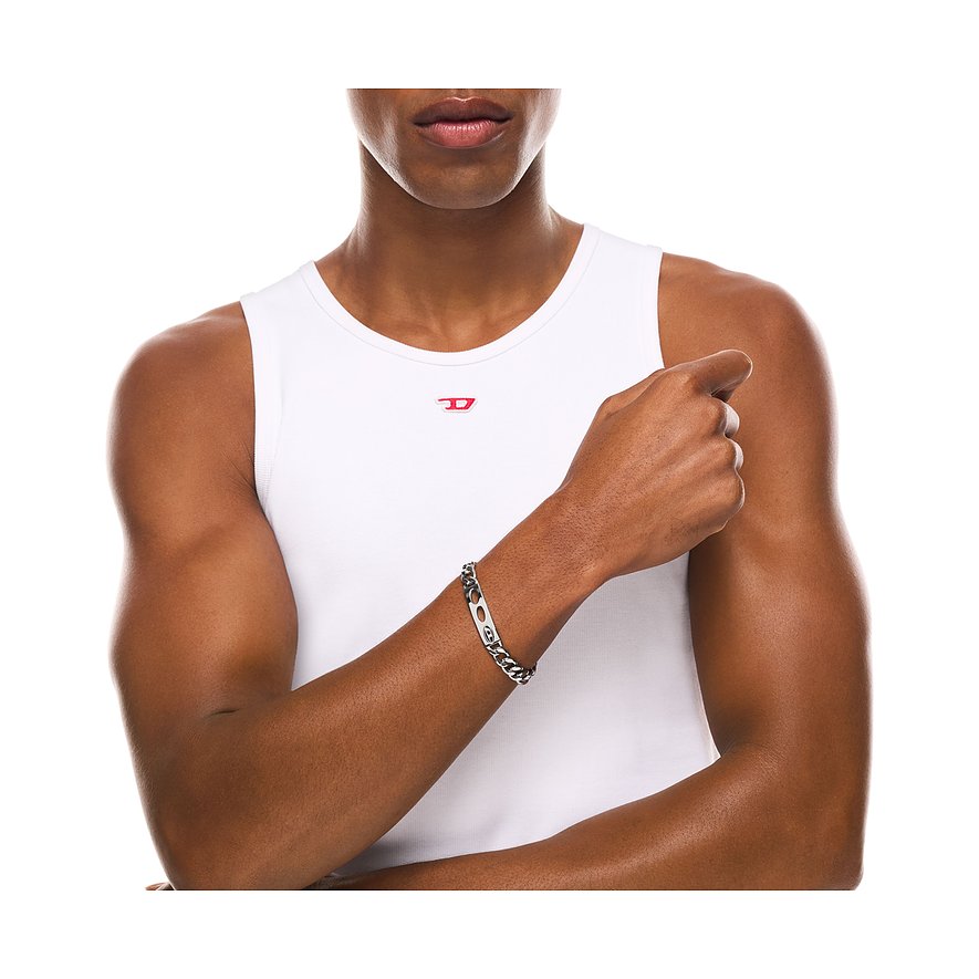 Nahaufnahme eines Mannes, der ein Diesel Armband aus Edelstahl mit Kettengliedern und einer ovalen Plakette trägt.