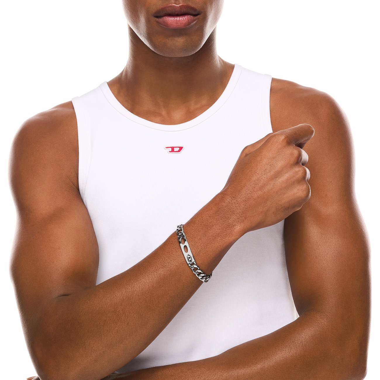 Nahaufnahme eines Mannes, der ein Diesel Armband aus Edelstahl mit Kettengliedern und einer ovalen Plakette trägt.