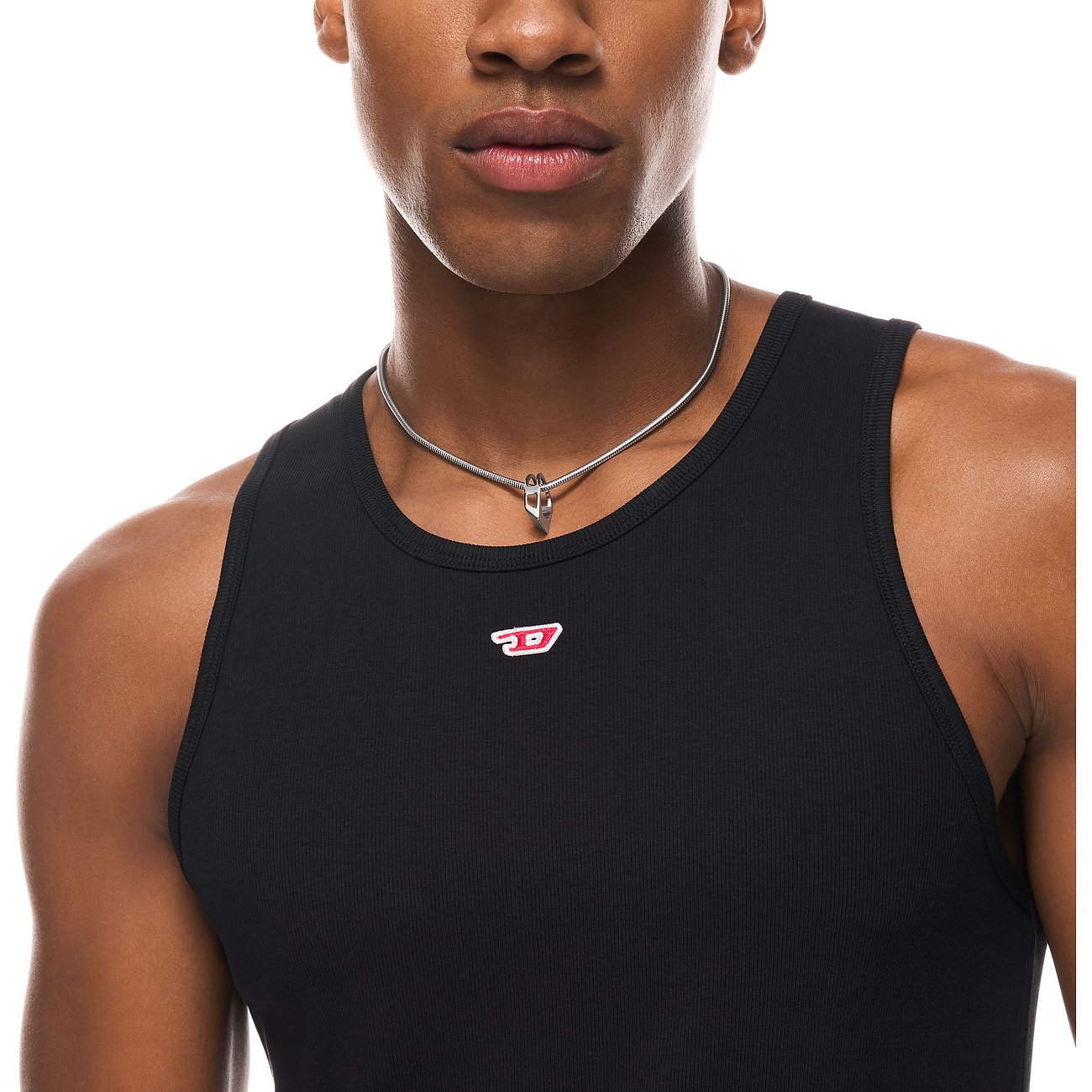 Närbild på en man som bär ett Diesel halsband i rostfritt stål. Smycket har ett litet hänge.