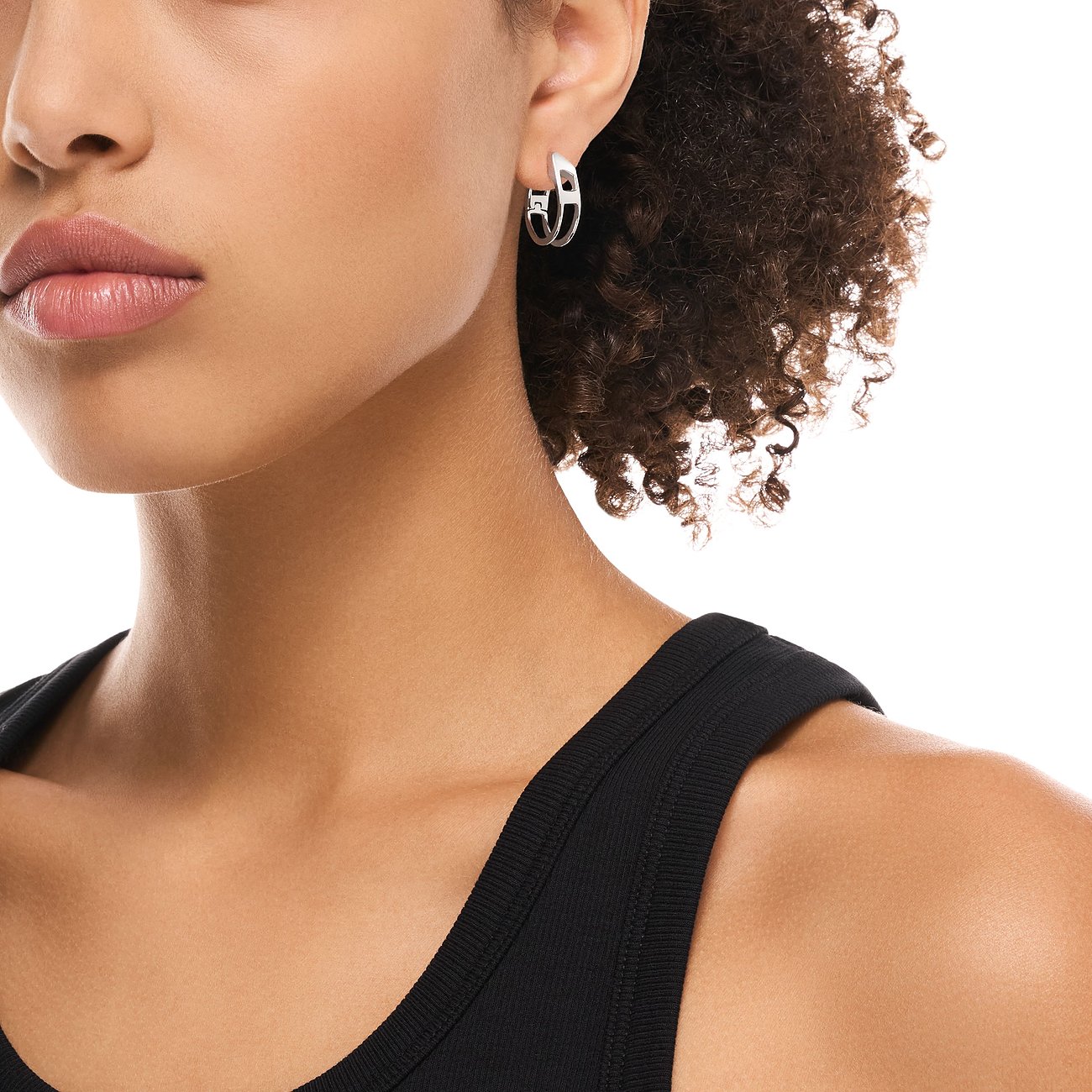 Närbild av en person med ett guldfärgat Diesel örhänge i rostfritt stål på höger öra, med modern utskuren design.