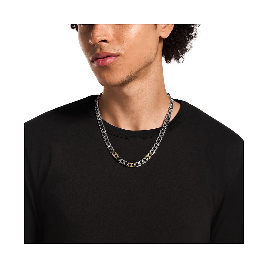 Ein junger Mann trägt eine Emporio Armani Halskette aus Edelstahl in Silber- und Goldtönen.