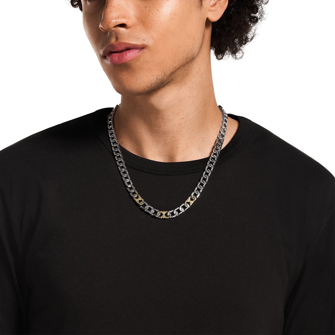 Ein junger Mann trägt eine Emporio Armani Halskette aus Edelstahl in Silber- und Goldtönen.