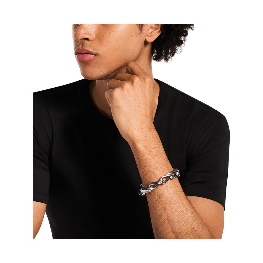 Ein Mann trägt ein Emporio Armani Armschmuck aus Edelstahl mit gewellten Gliedern am rechten Arm.