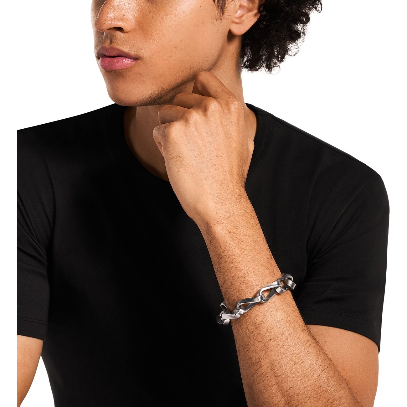 Ein Mann trägt ein Emporio Armani Armschmuck aus Edelstahl mit gewellten Gliedern am rechten Arm.