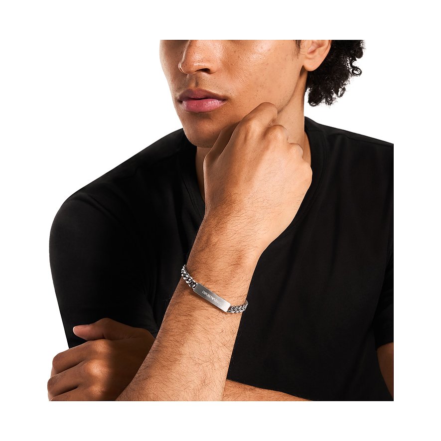 Un uomo indossa un bracciale Emporio Armani in acciaio inossidabile con catena a maglie e barretta incisa.
