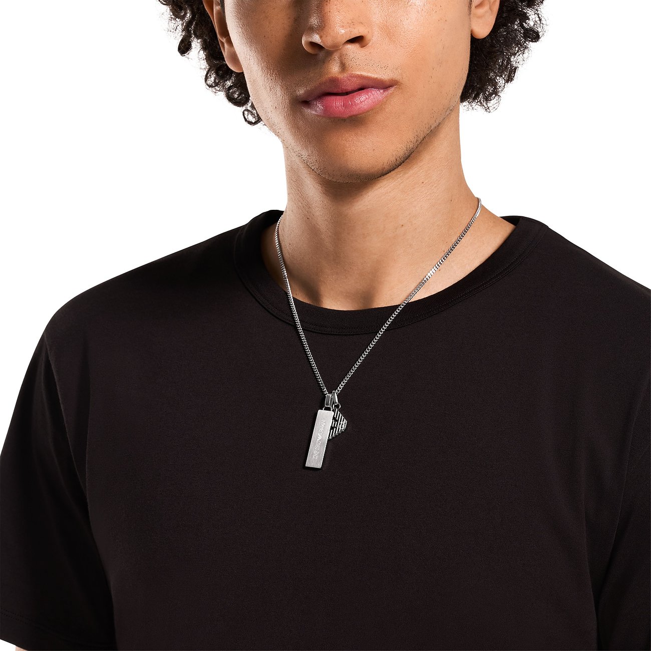 Homme en T-shirt noir portant un collier Emporio Armani en acier inoxydable avec pendentifs barre et aigle.