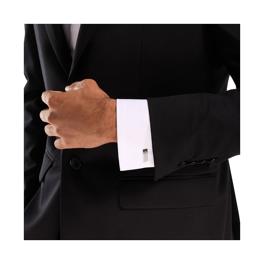 Un uomo in abito nero indossa gemelli Emporio Armani in acciaio inossidabile con una camicia bianca.