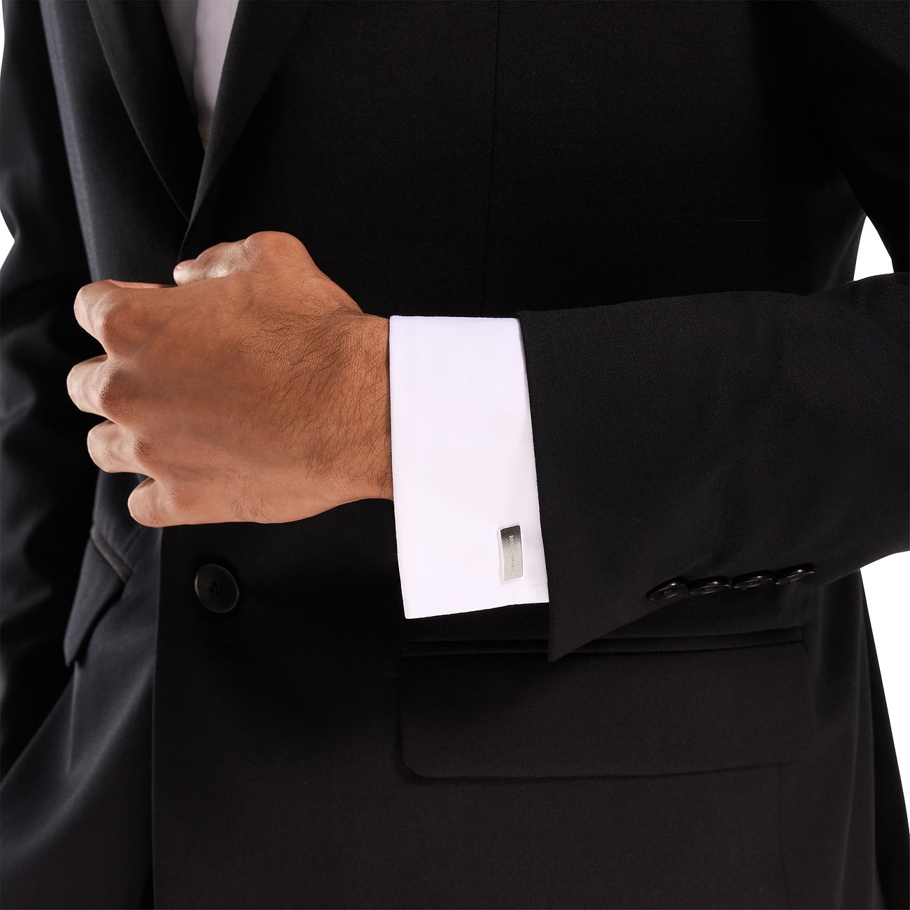 Un uomo in abito nero indossa gemelli Emporio Armani in acciaio inossidabile con una camicia bianca.