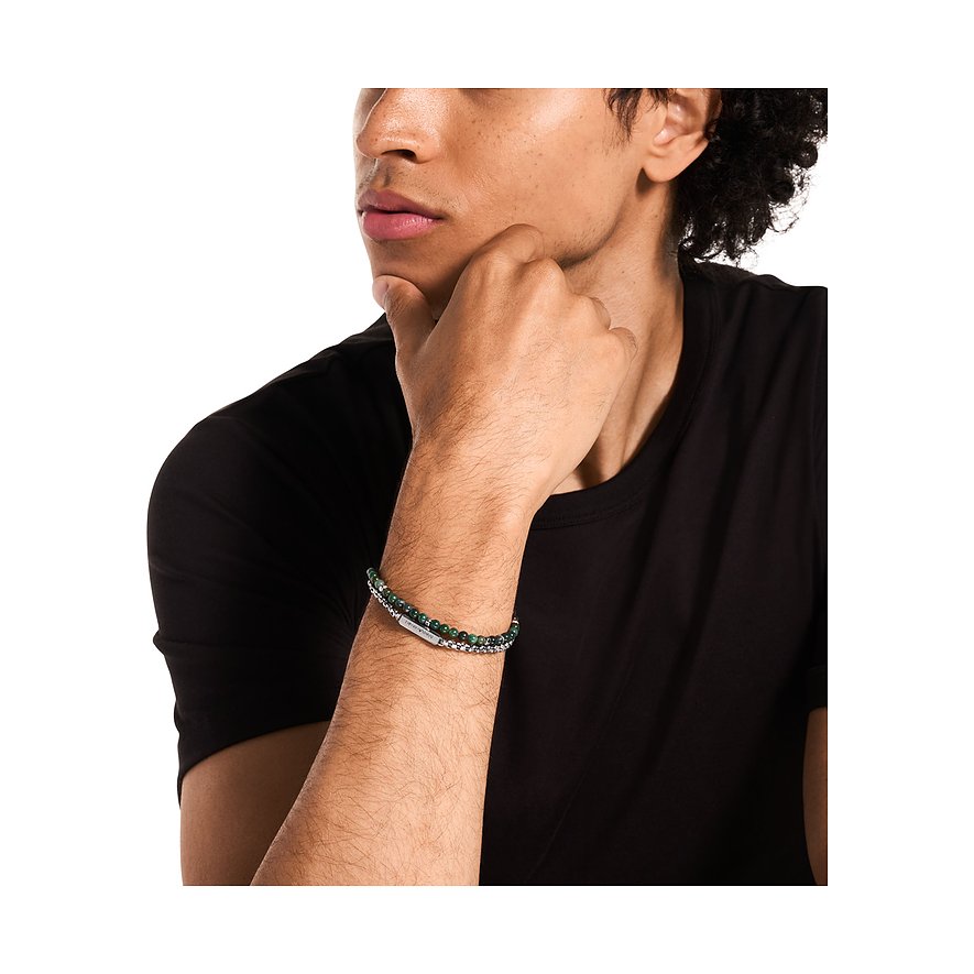 En man bär ett Emporio Armani-armband i rostfritt stål och grön agatsten på höger handled.