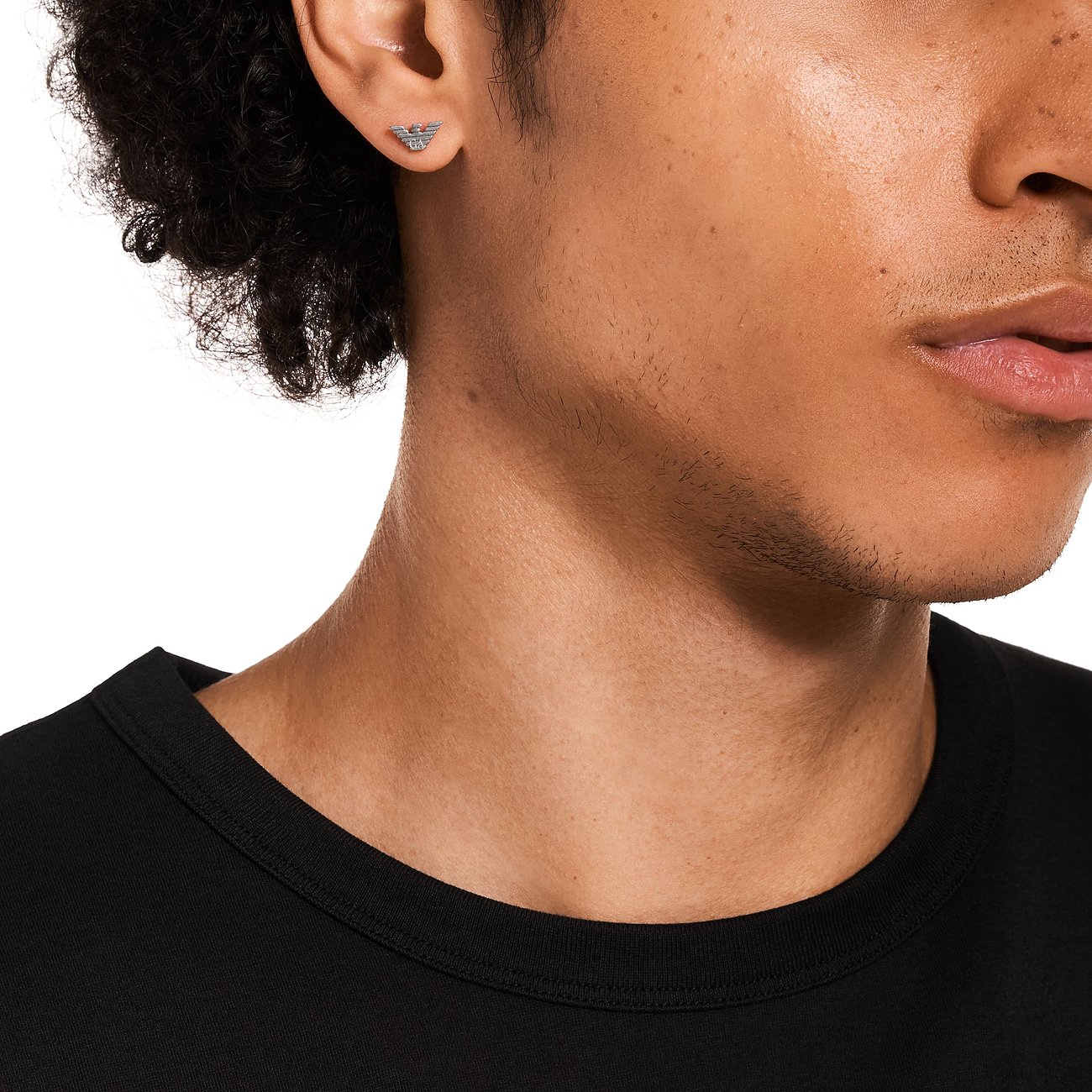 Nahaufnahme eines Ohres, das einen Emporio Armani Ohrstecker aus Edelstahl mit dem Markenlogo tr&aumlgt.