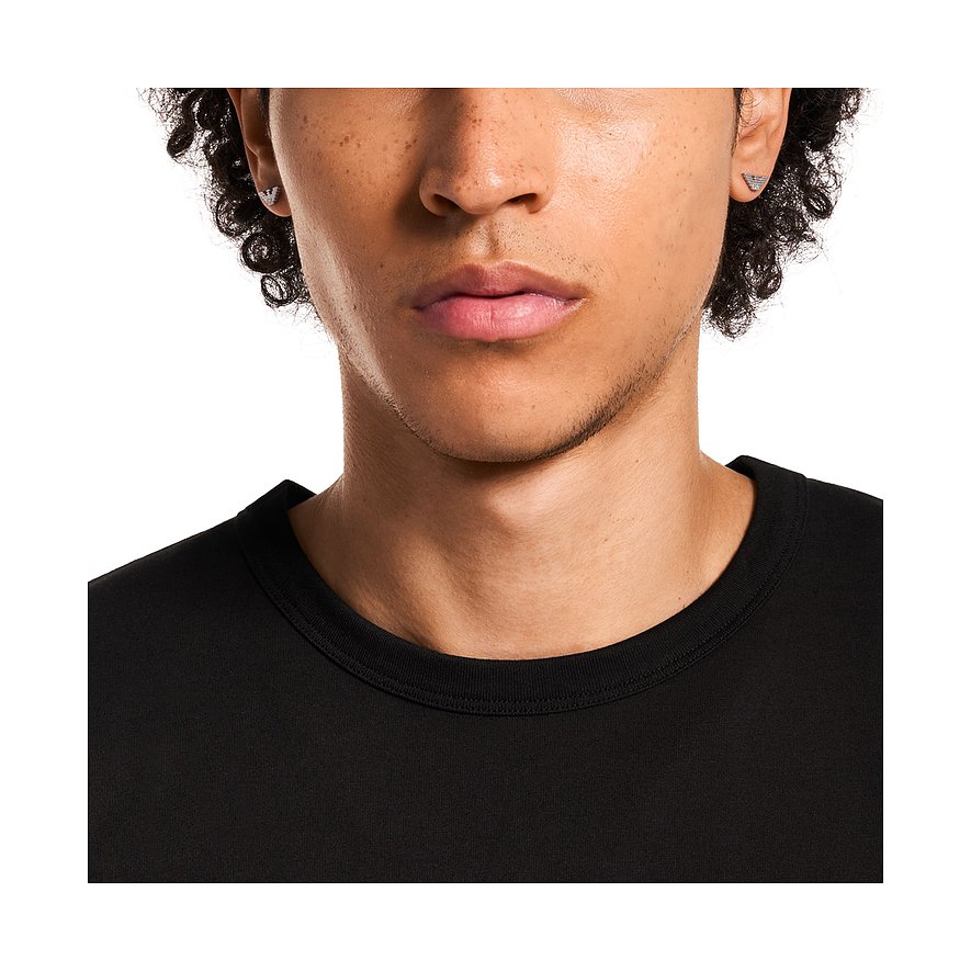 Nahaufnahme eines Mannes, der Emporio Armani Ohrringe aus Edelstahl mit einem Adler-Logo-Motiv trägt.