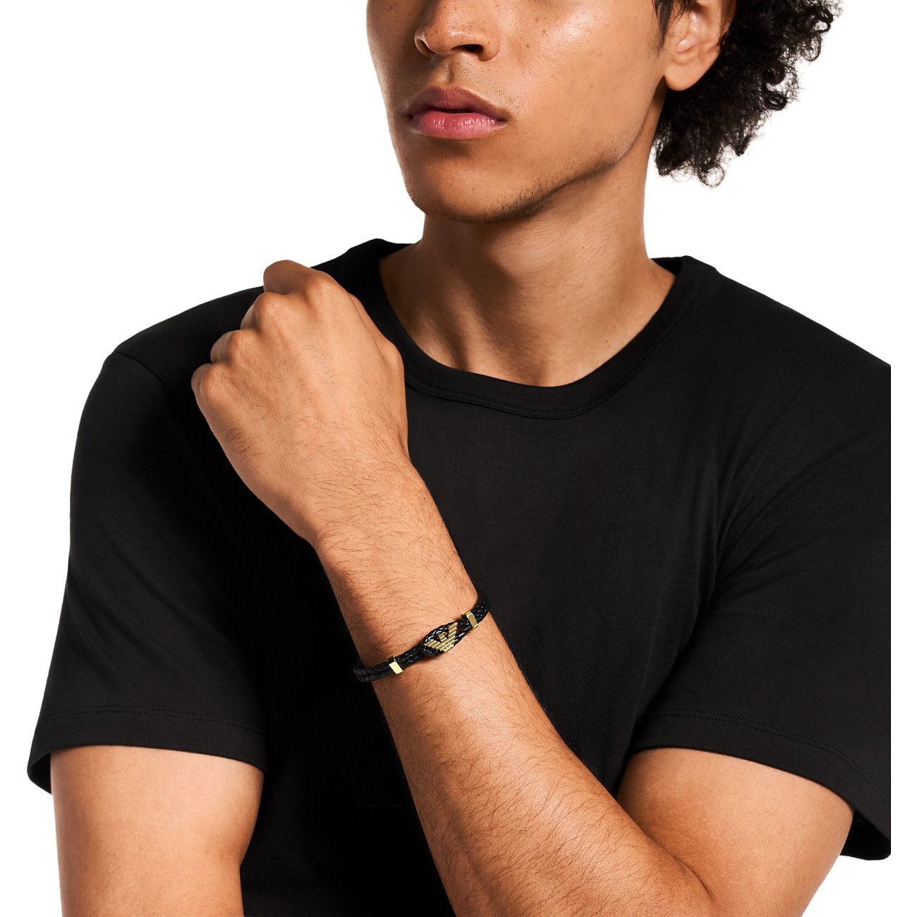 En man bär ett Emporio Armani-armband i läder och rostfritt stål med gulddetaljer på handleden.