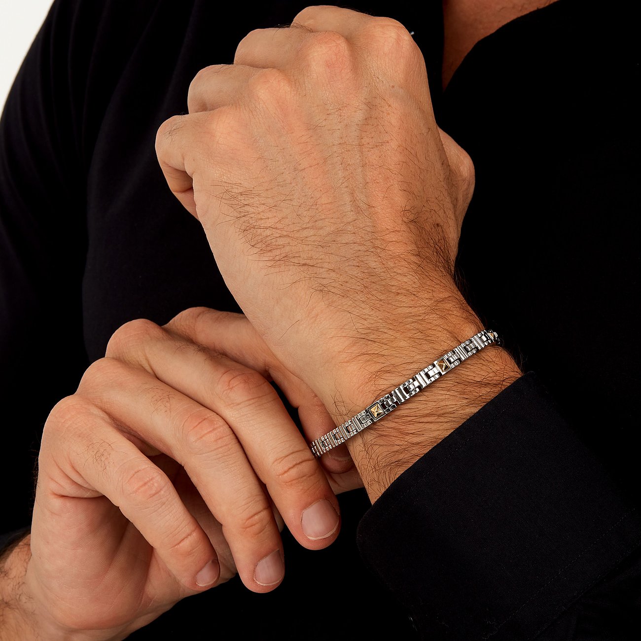 Morellato Armband aus Edelstahl und Gelbgold (750) an einem behaarten Arm, der ein schwarzes Hemd trägt.