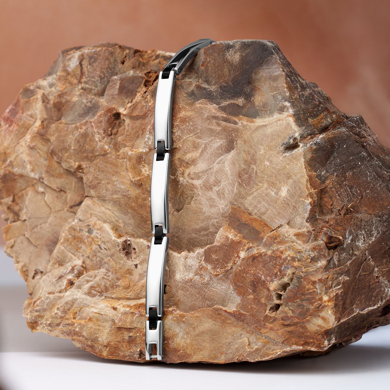 Das Morellato Armband aus glänzendem Edelstahl zeigt abwechselnd silberne und schwarze Glieder auf einem Felsen.