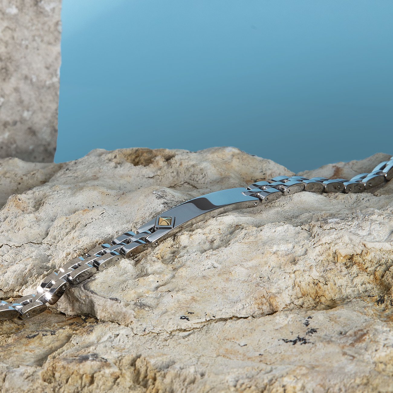 Morellato-Armband aus Edelstahl und Gelbgold auf beigem Felsen aus der Vogelperspektive gesehen.