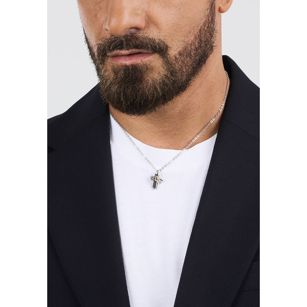 En mand i sort blazer og hvid T-shirt bærer en Morellato halskæde i rustfrit stål med korsformet vedhæng.