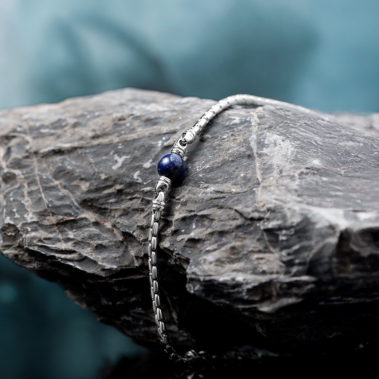 Morellato Armschmuck aus Edelstahl mit einem dunkelblauen Lapislazuli-Farbstein in der Mitte, auf einem Felsen.
