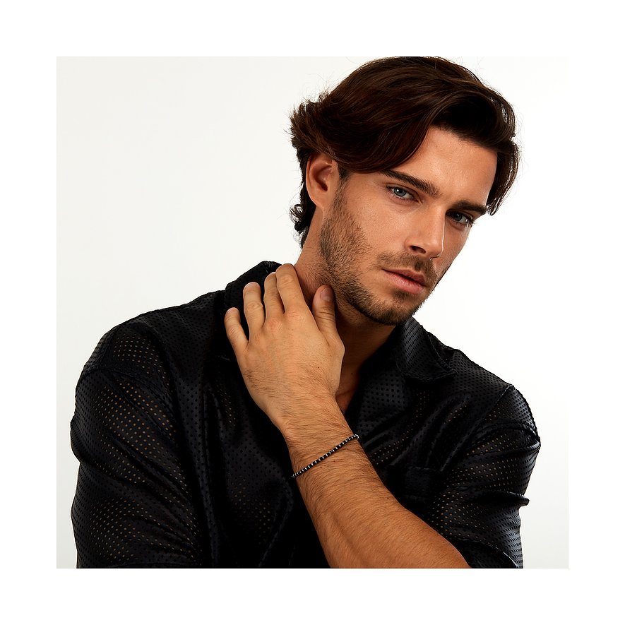 En man med blågrå ögon bär ett Morellato armband i rostfritt stål med fasetterad agat på sin högra underarm.