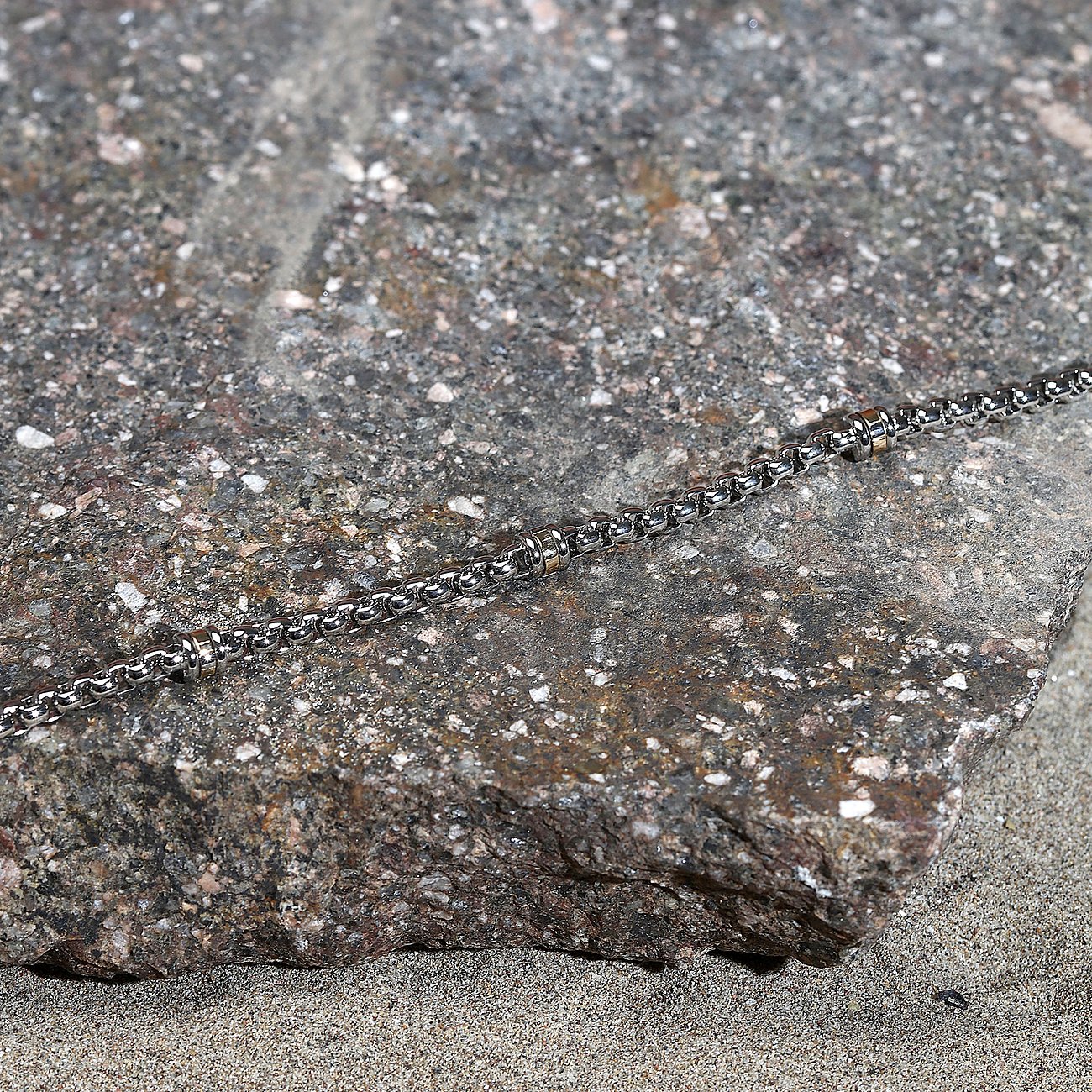 Nærbillede af Morellato armbånd i guldfarvet rustfrit stål på en sten.