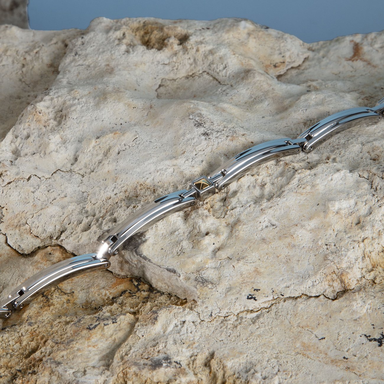 Morellato Armschmuck aus Edelstahl und Gelbgold, liegend auf einem hellbeigen Felsen.