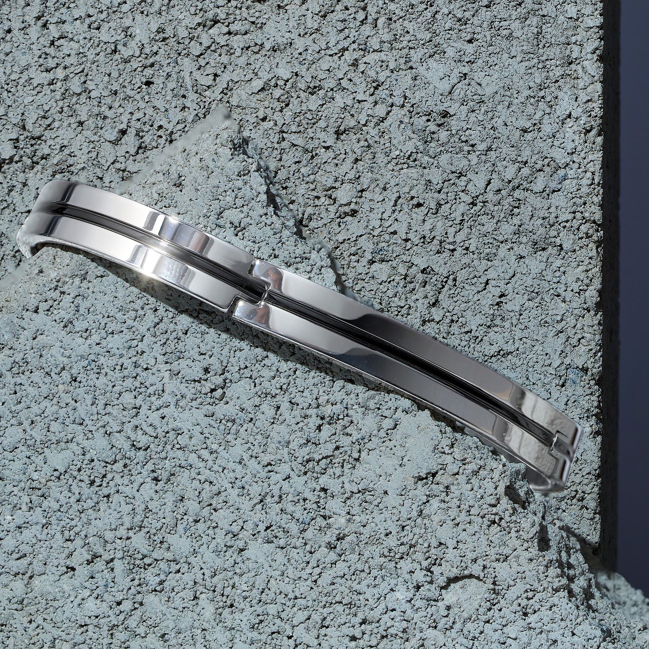 Das schlichte Morellato Armband aus glänzendem Edelstahl liegt diagonal auf einem rauen, grauen Untergrund.