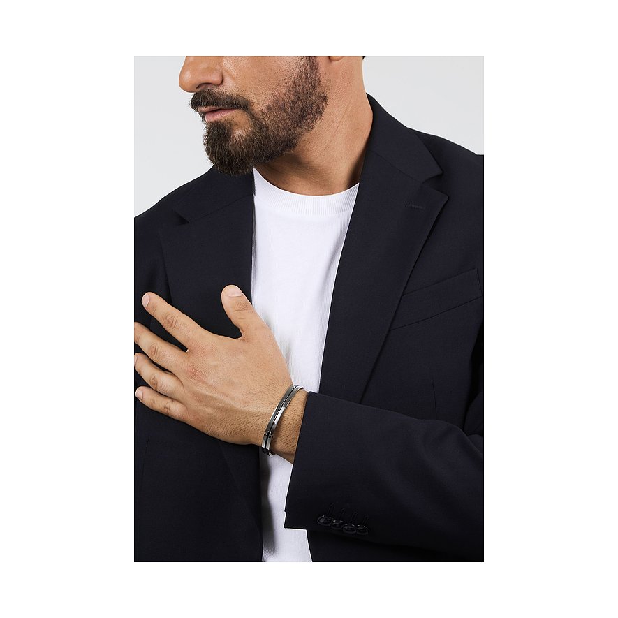 Nahaufnahme eines Mannes im Anzug, dessen Hand auf der Brust liegt und ein Morellato Armschmuck aus Edelstahl trägt.