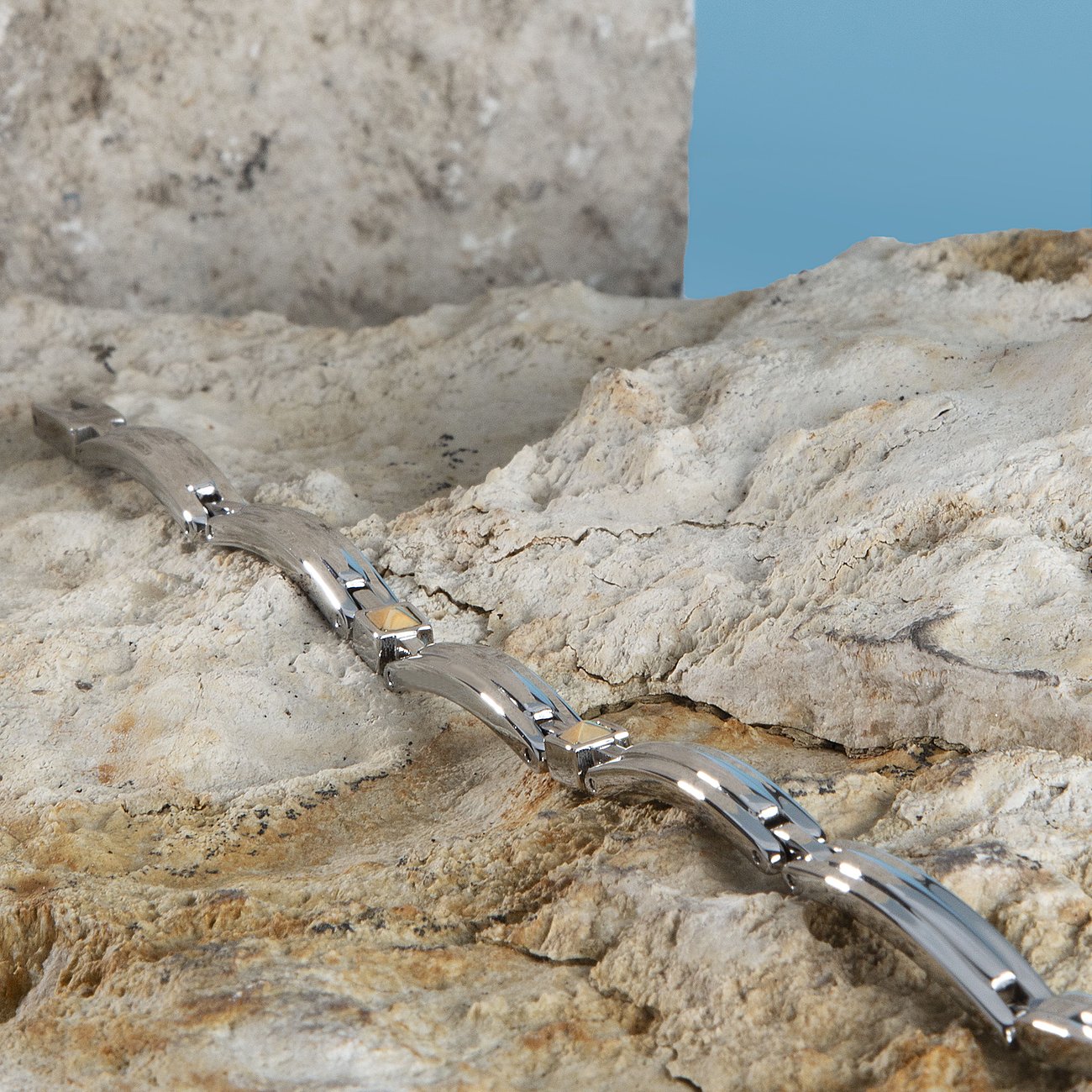 Ein Morellato Armschmuck aus gelbgoldenem 750er Gold und Edelstahl liegt schräg auf einem Stein.