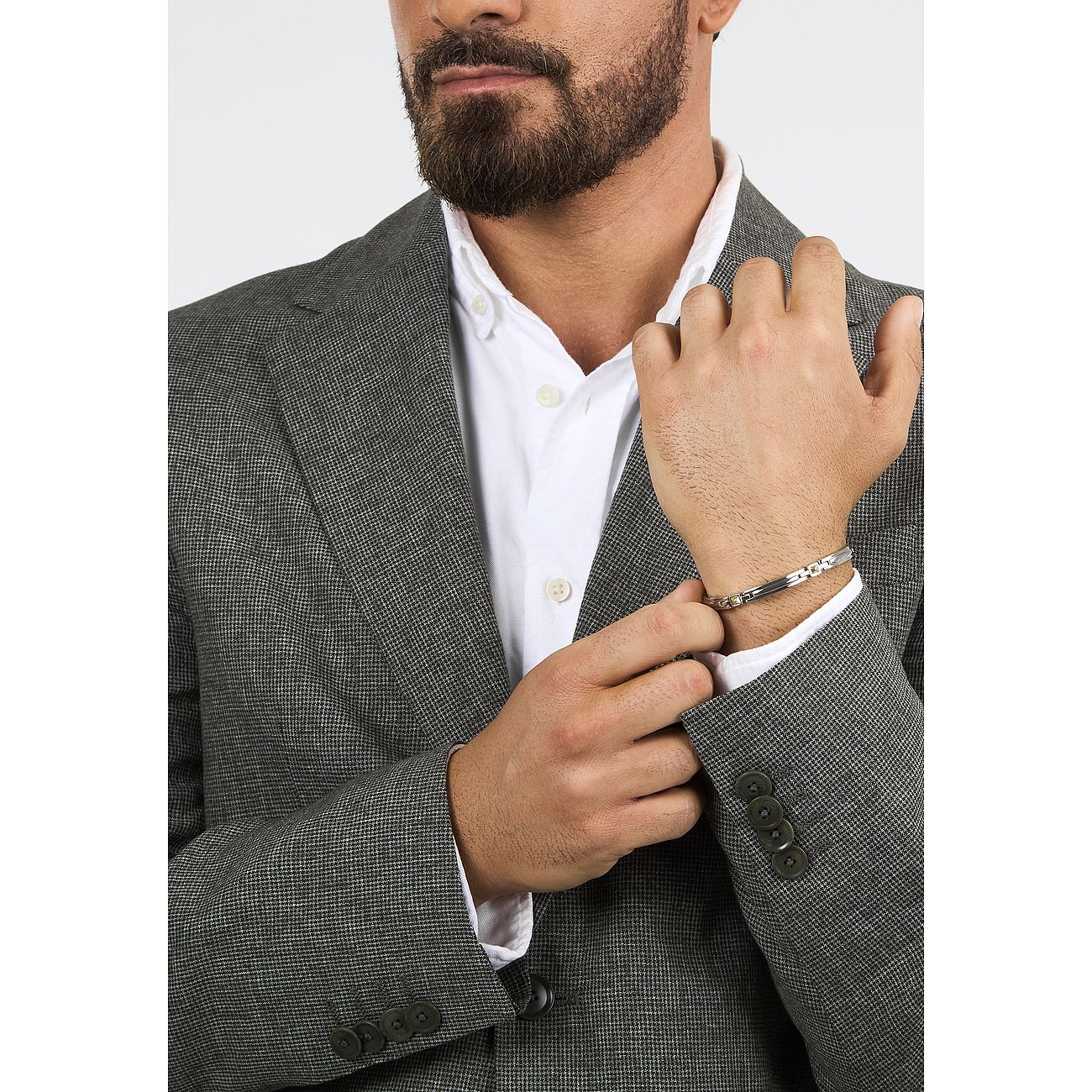 Ein Mann mit Bart und Anzug trägt ein zweifarbiges Morellato Armband aus Edelstahl und Gelbgold am Handgelenk.