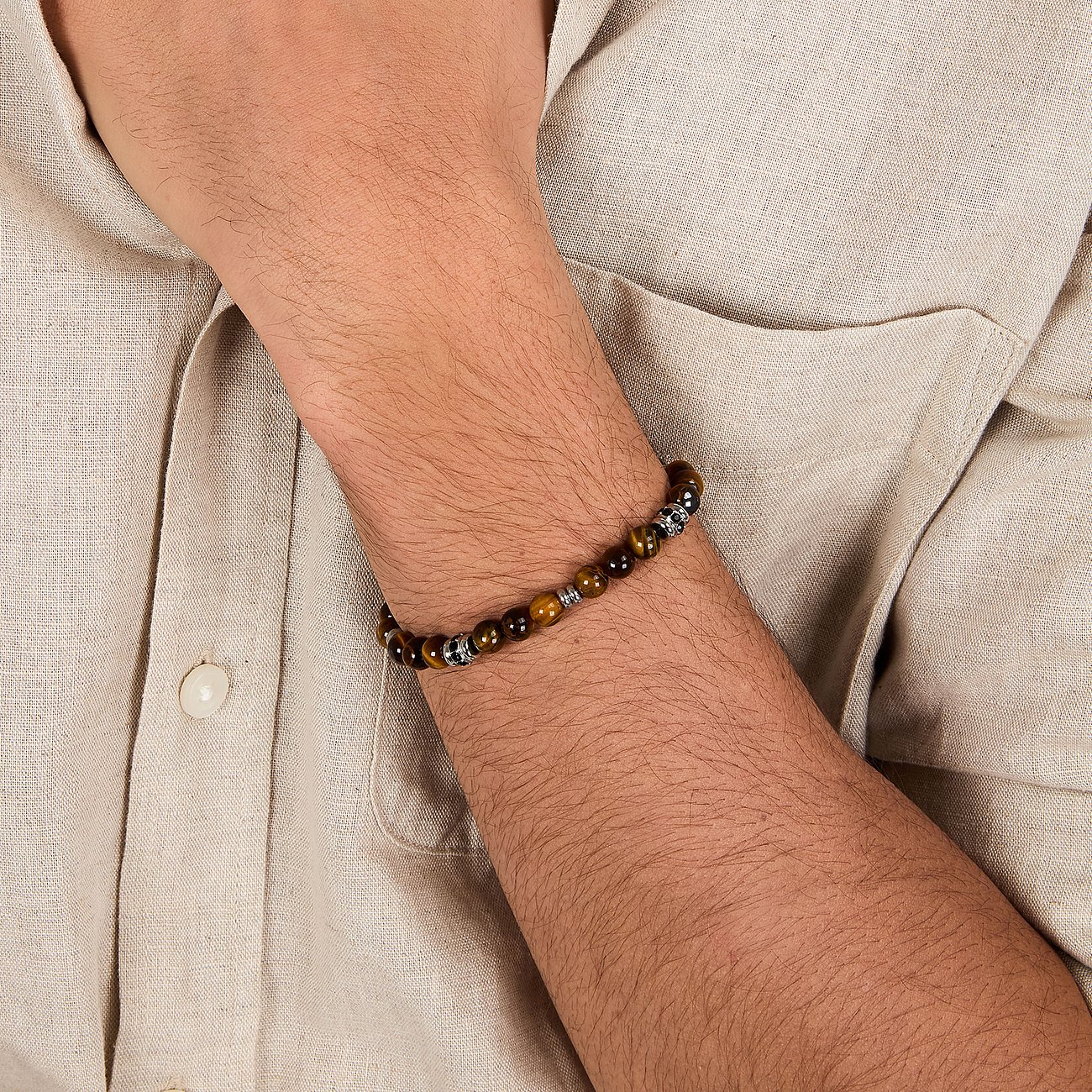 Morellato Armschmuck aus Edelstahl mit Tigerauge Farbsteinen am Handgelenk eines Mannes.