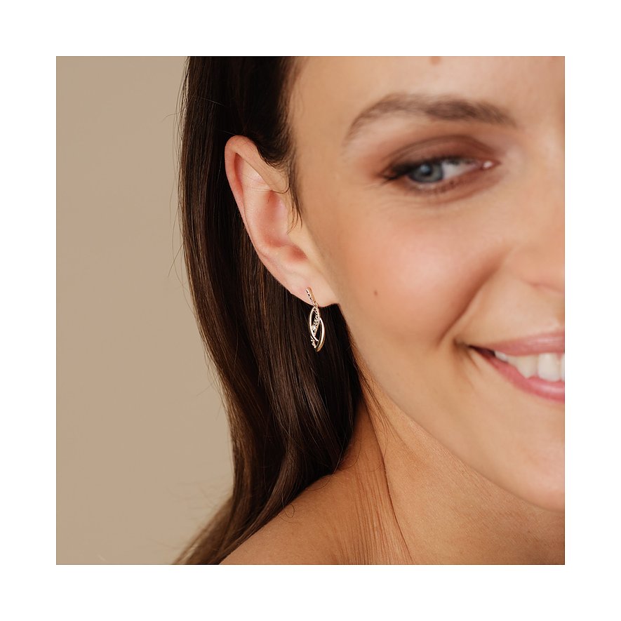 Ein CHRIST Ohrring aus 375er Gelbgold mit Diamanten hängt am Ohr einer Frau.