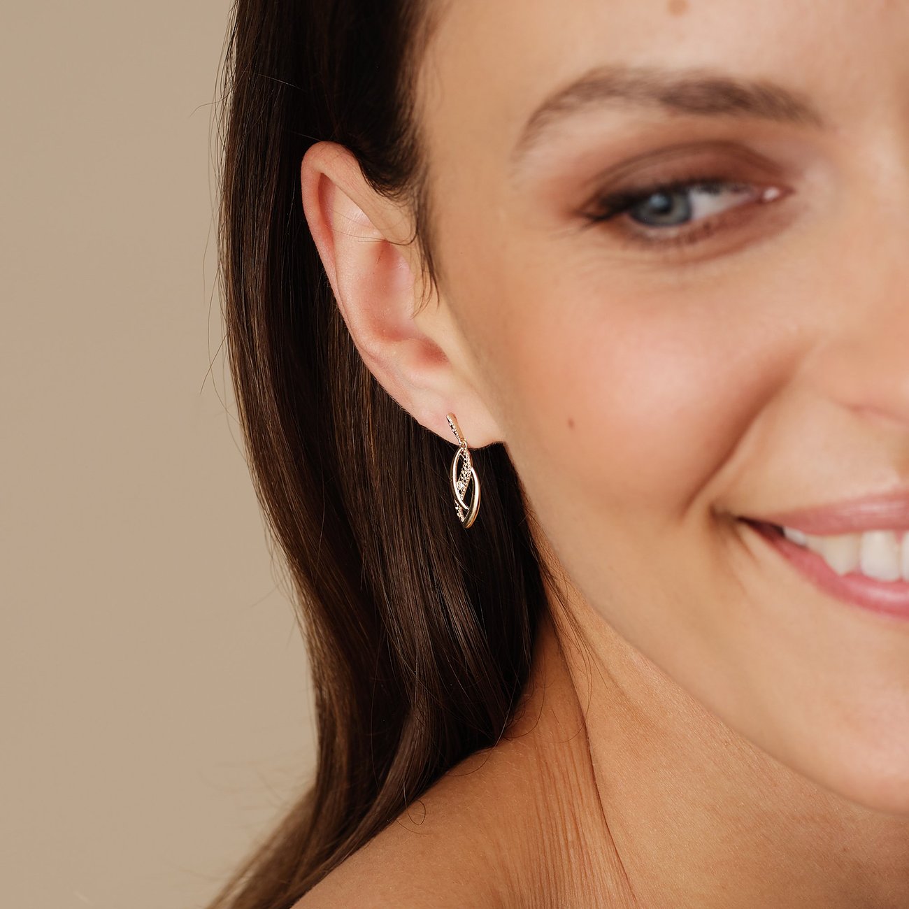 Ein CHRIST Ohrring aus 375er Gelbgold mit Diamanten hängt am Ohr einer Frau.