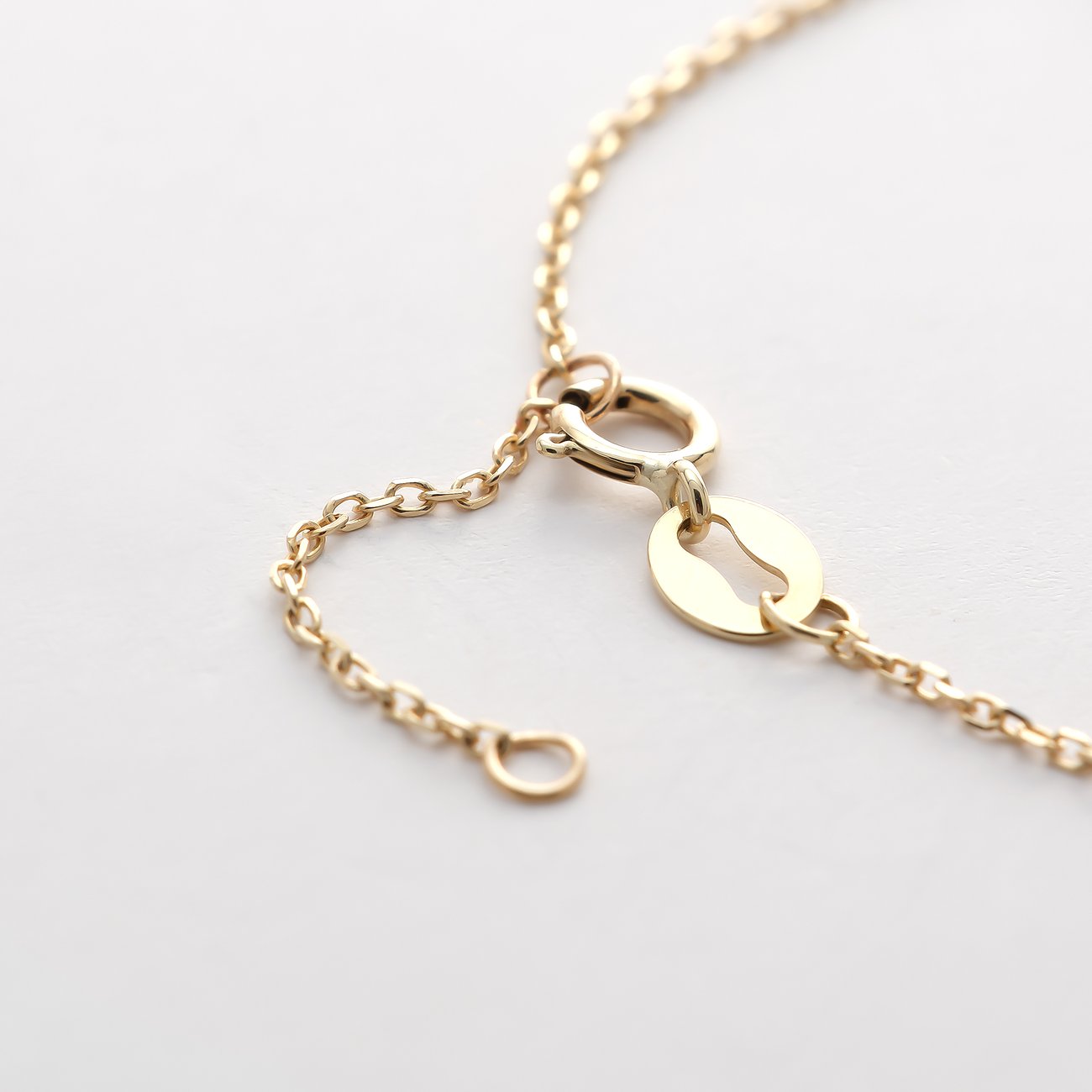 Detailansicht eines Verschlusses und Verlängerungskettchens eines FAVS Little Friends Gelbgold-Armbands auf weißem Hintergrund.