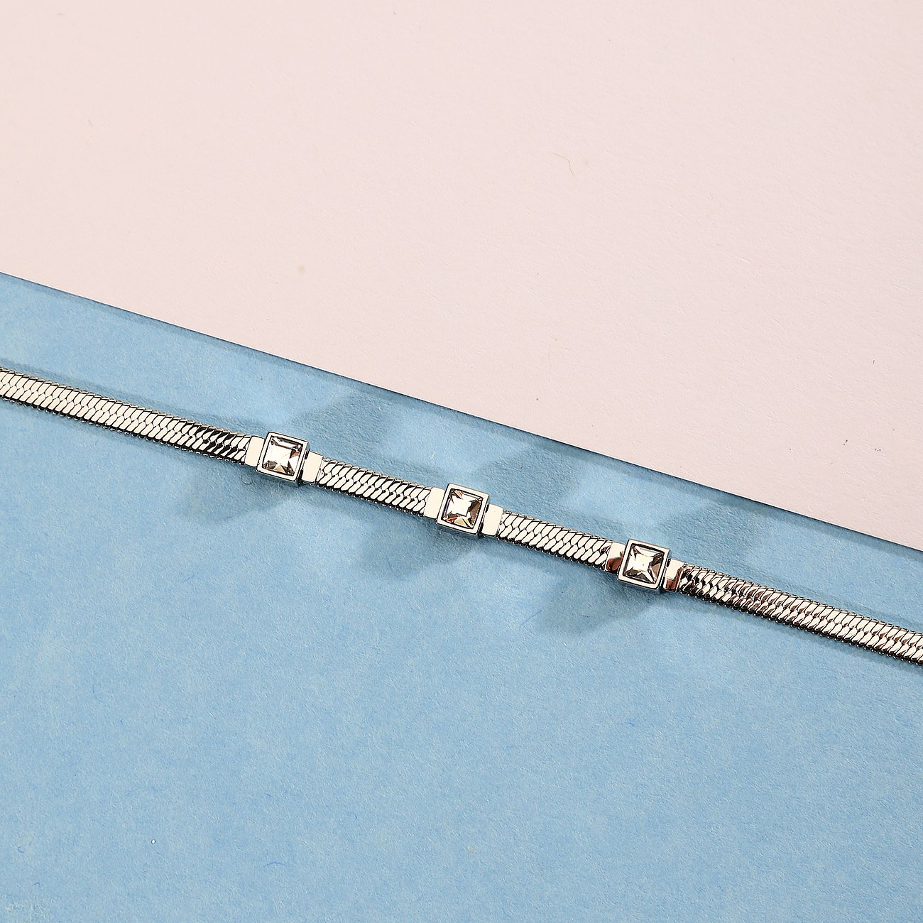 Ein silbernes Morellato Edelstahlarmband mit flachen Gliedern und drei quadratischen Kristallen, schräg von oben.