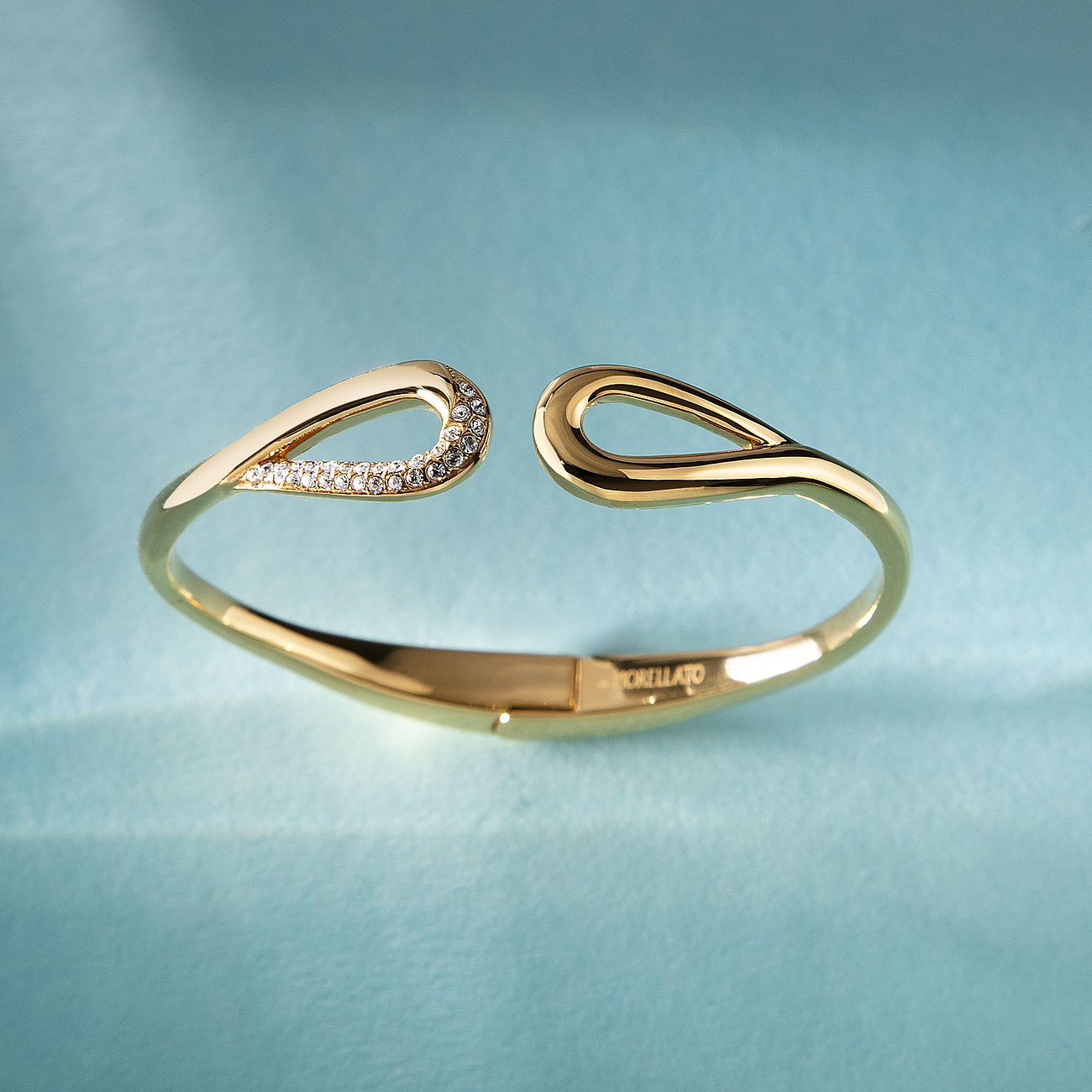 Ein goldenes Morellato Armband aus Edelstahl mit geschwungenen Enden, von denen eines mit Kristallen verziert ist.