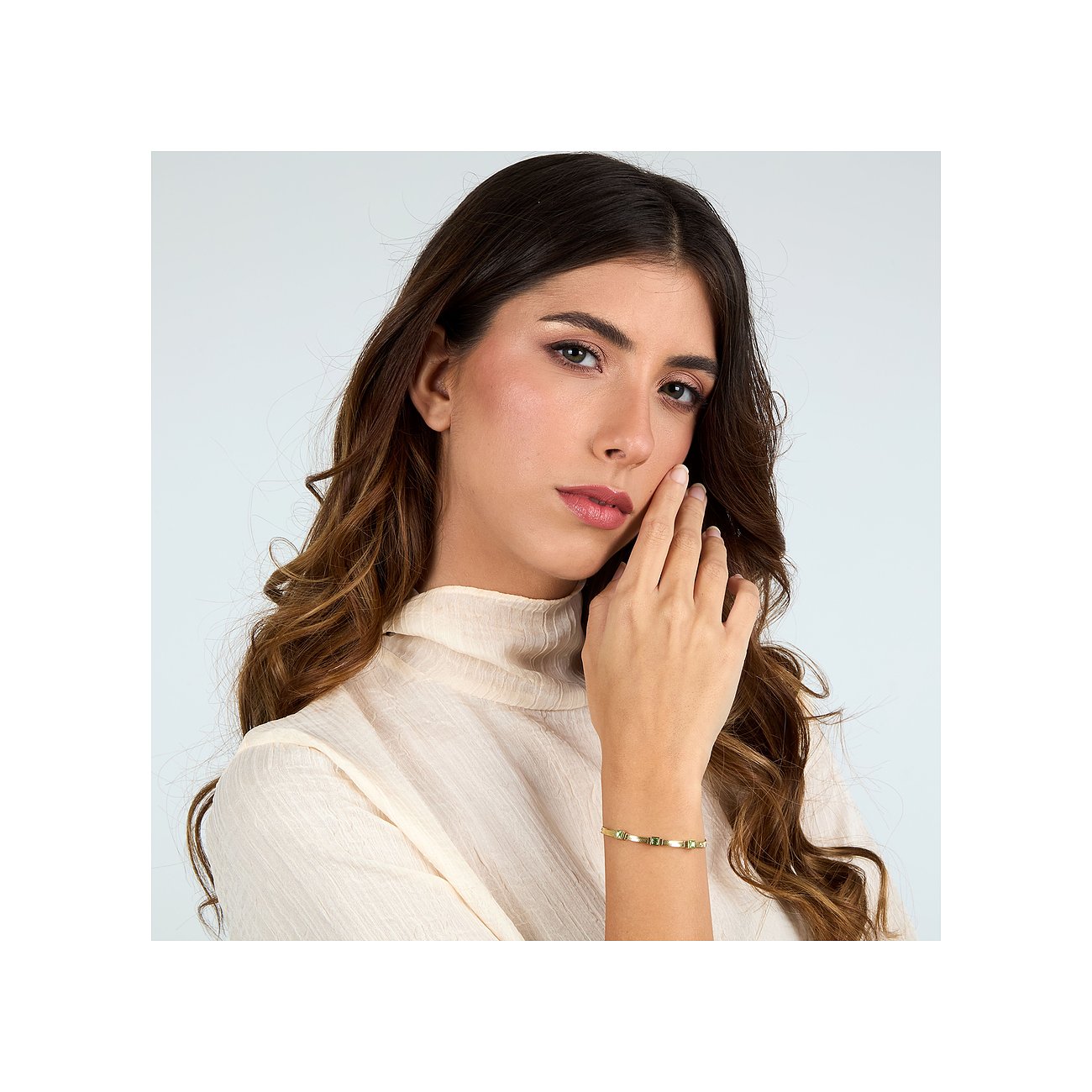 Una donna indossa un elegante bracciale Morellato dorato in acciaio inox con pietre di cristallo verde al polso.