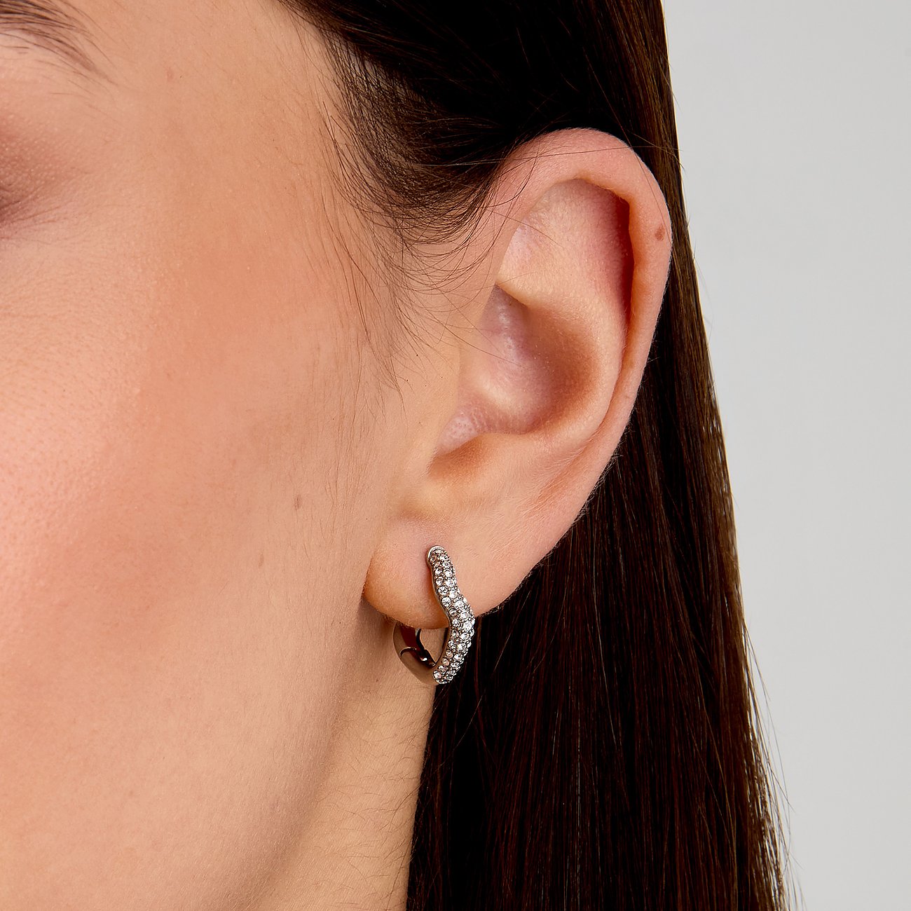 Ein Morellato Ohrschmuck aus Edelstahl, halbherzförmig, ist mit Kristall-Farbsteinen besetzt und wird am Ohr getragen.