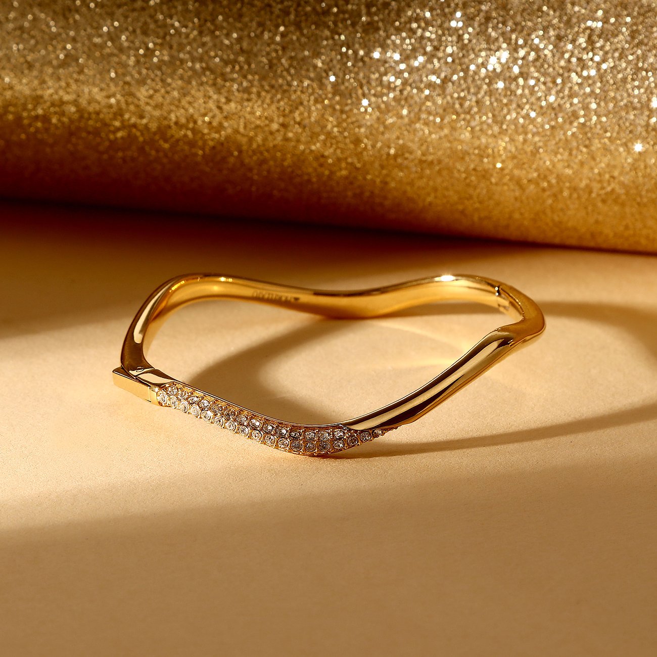 Morellato Armschmuck aus vergoldetem Edelstahl mit einer Welle aus glänzenden Kristallen im Vordergrund.
