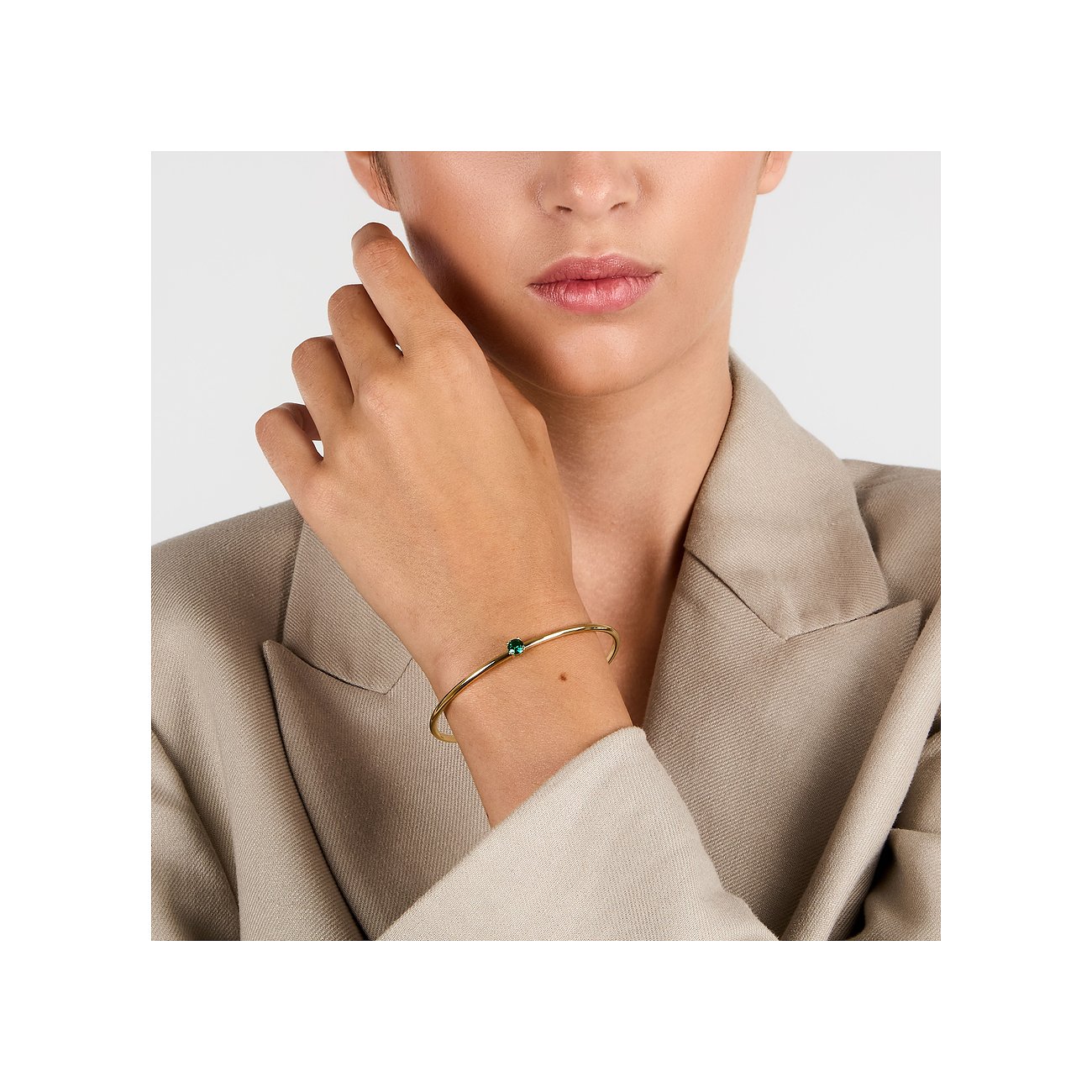 Nahaufnahme eines goldenen Morellato Edelstahl-Armreifs mit einem grünen Zirkonia Farbstein am Handgelenk eines Models.