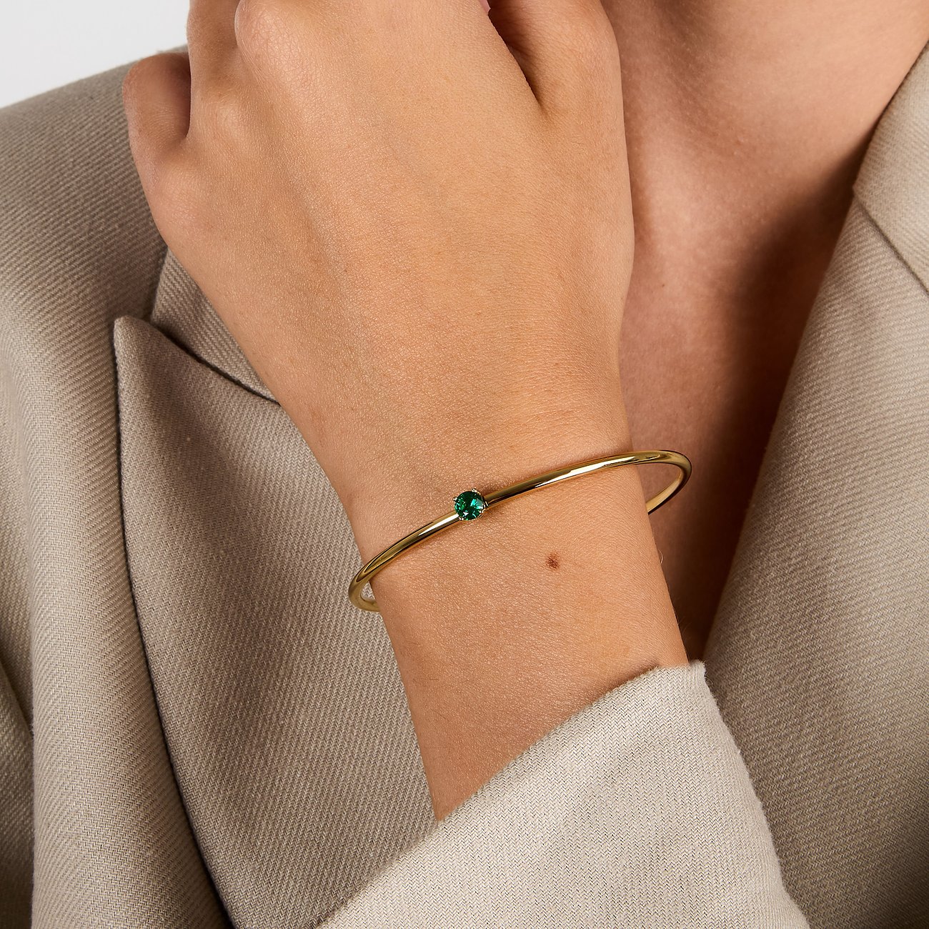 Am Handgelenk getragener Morellato Armschmuck aus goldenem Edelstahl mit einem grünen Zirkonia-Farbstein.