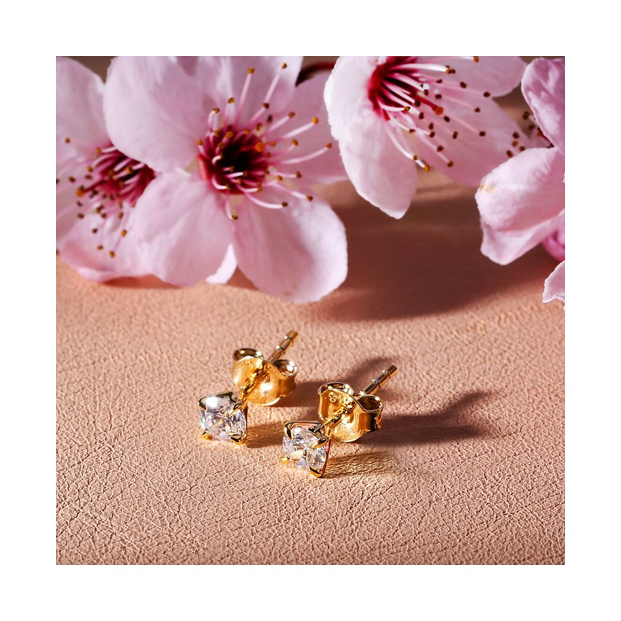 CHRIST oorstekers van 585 geelgoud met fonkelende diamanten als hoofdstenen, gepresenteerd voor roze bloesems.