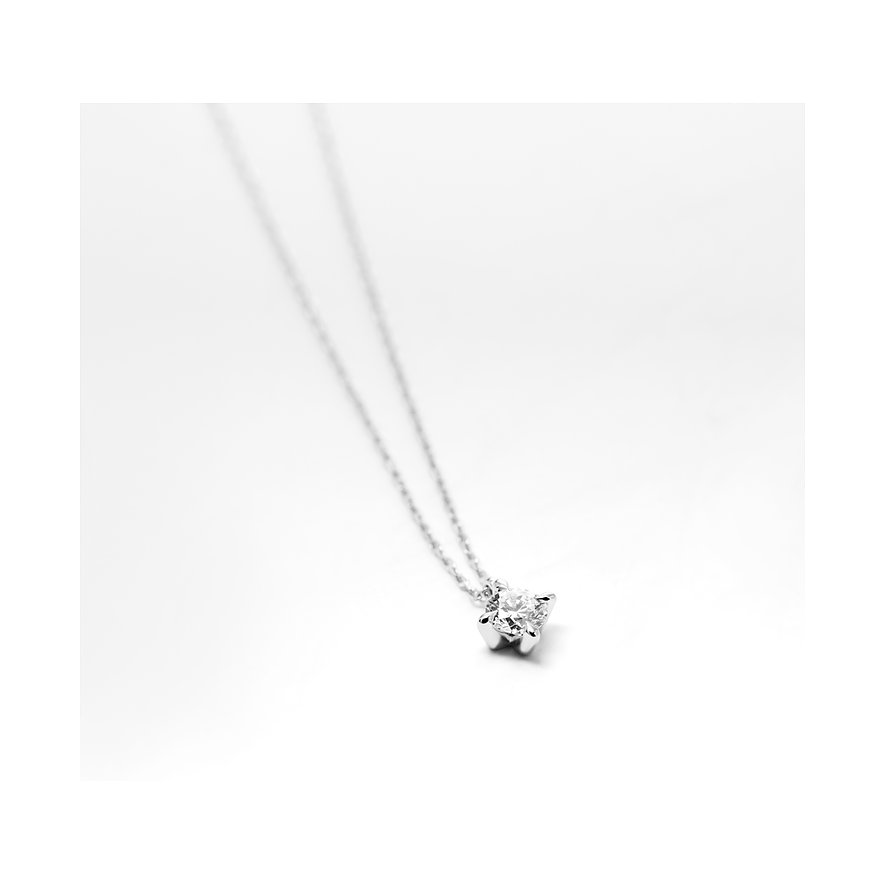 CHRIST Halsschmuck aus 585 Weißgold mit einem funkelnden Diamanten als Solitär-Anhänger, auf beigem Untergrund.