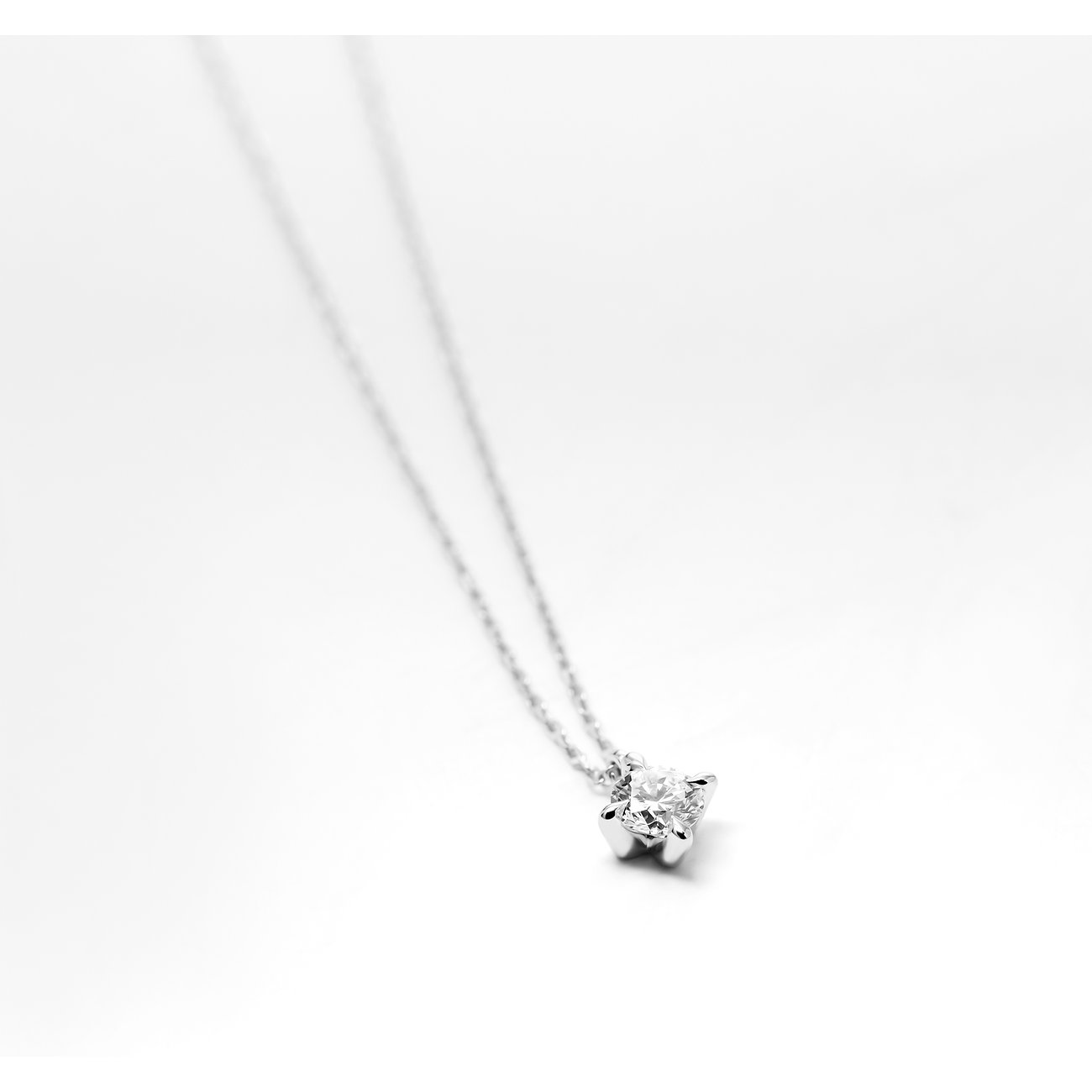 CHRIST Halsschmuck aus 585 Weißgold mit einem funkelnden Diamanten als Solitär-Anhänger, auf beigem Untergrund.