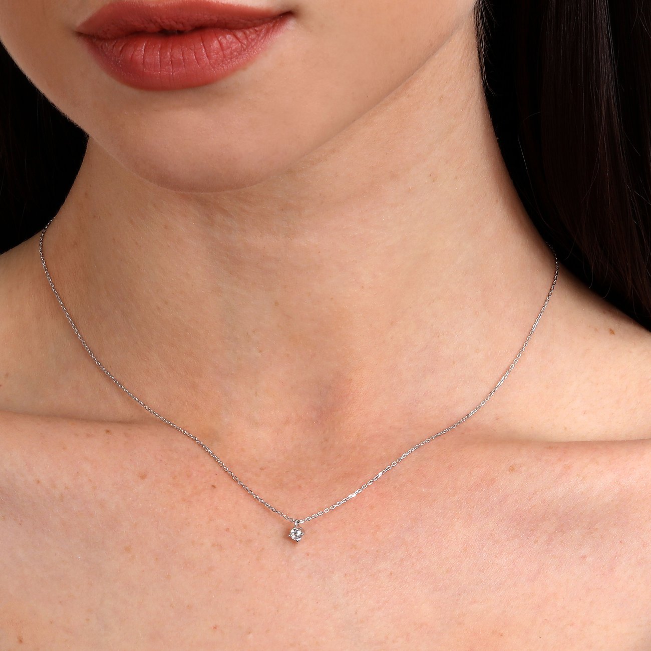 Nahaufnahme eines minimalistischen CHRIST 585 Weißgold-Halsschmucks mit Diamant-Anhänger, getragen von einem Modell.