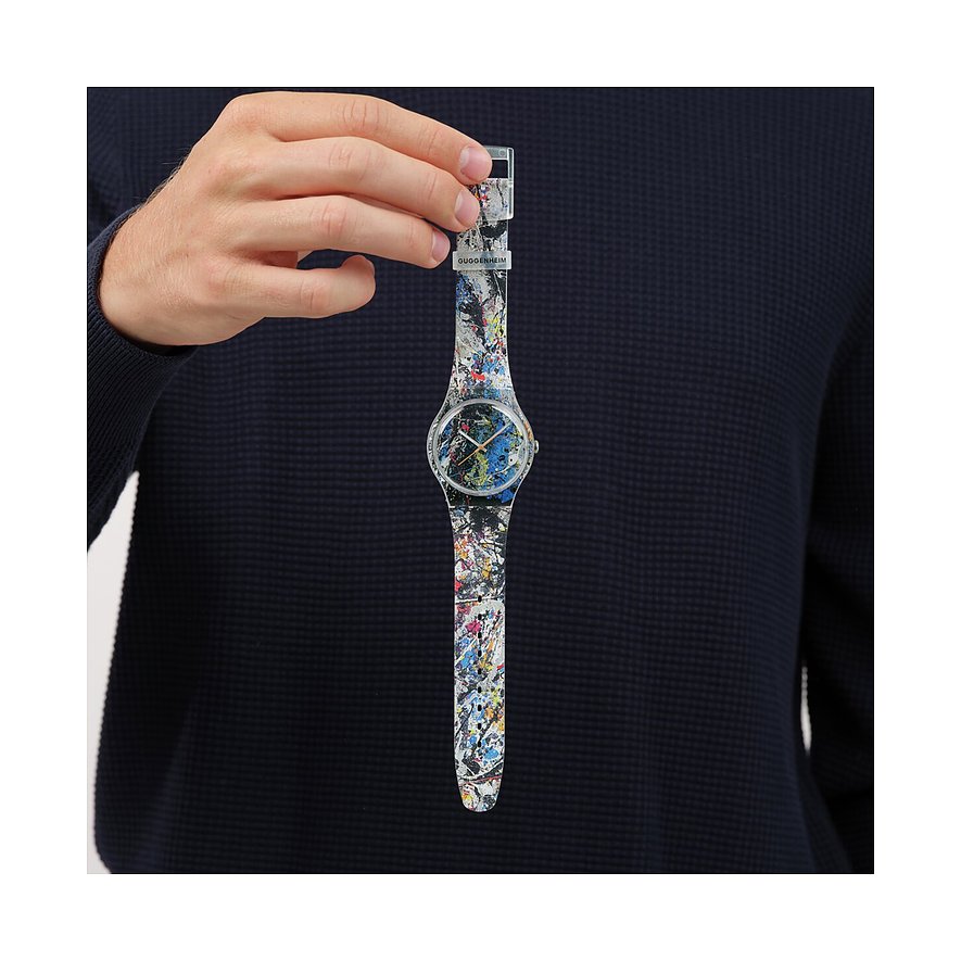 En mand holder et Swatch unisex-ur af plast med et farverigt stænkmønster i hånden.