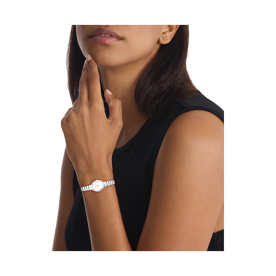 Nahaufnahme einer Calvin Klein Damenuhr aus Edelstahl mit ovalem Gehäuse und weißem Zifferblatt am Handgelenk eines Models.