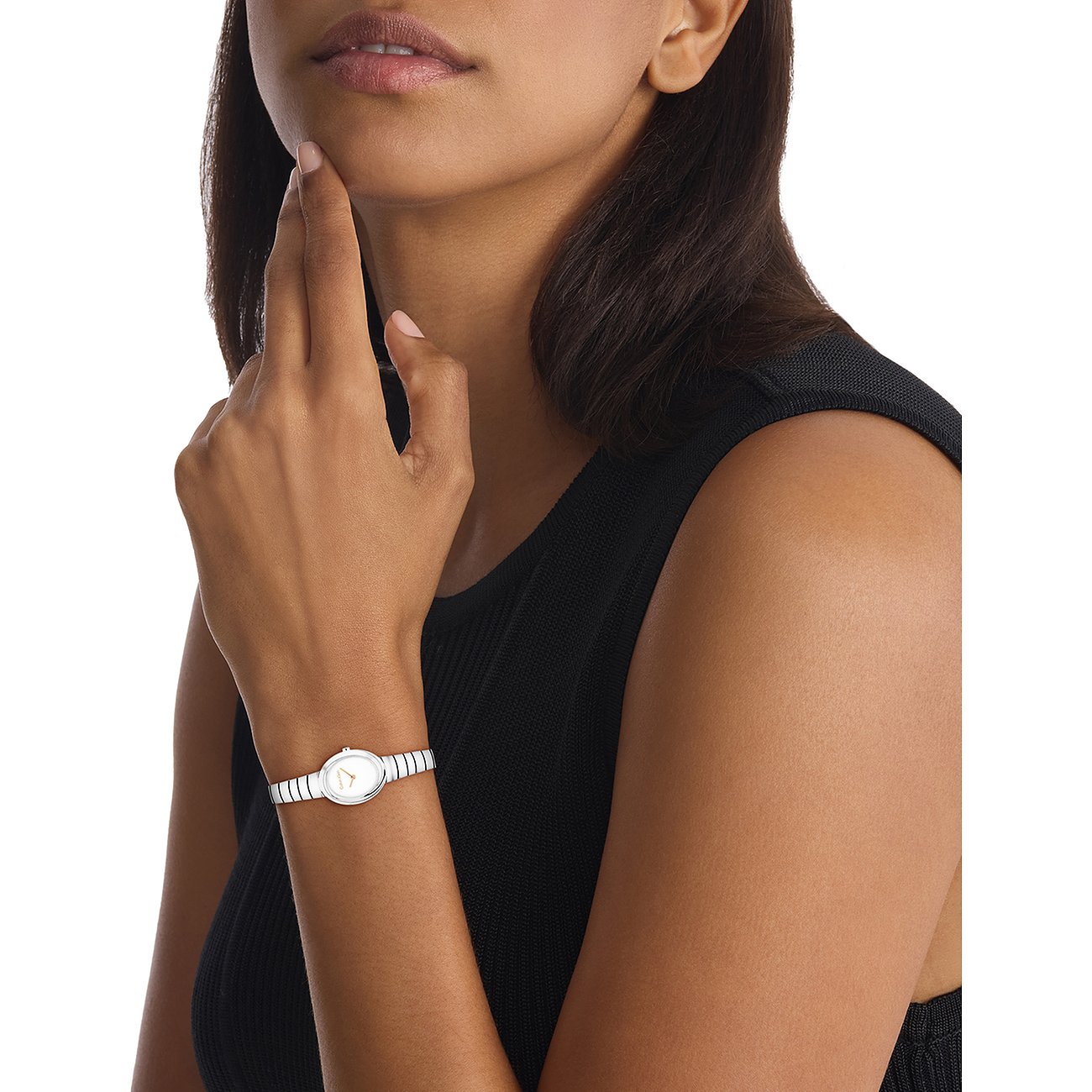 Nahaufnahme einer Calvin Klein Damenuhr aus Edelstahl mit ovalem Gehäuse und weißem Zifferblatt am Handgelenk eines Models.