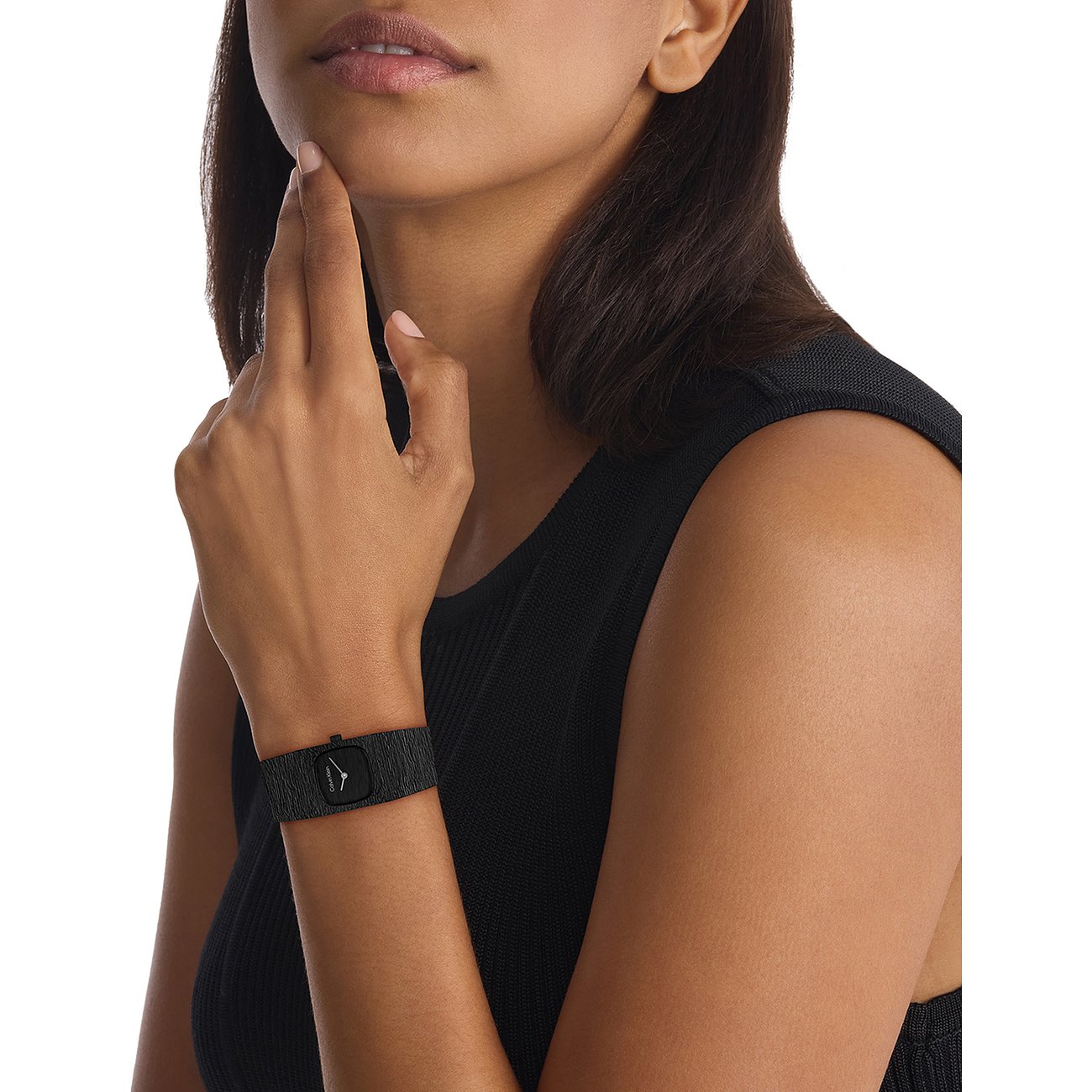 Eine Frau trägt eine Calvin Klein Damenuhr aus Edelstahl mit rechteckigem Zifferblatt und schwarzem Armband.